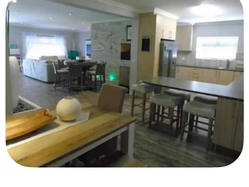 Open-plan living area featuring a modern kitchen with island, stone feature wall, and integrated dining space, creating a cohesive and functional layout.