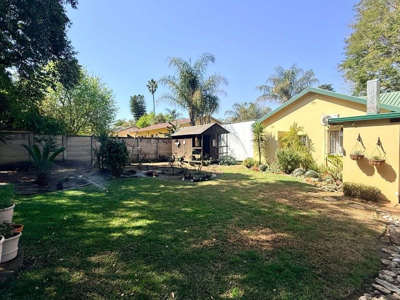 A spacious rear garden featuring a well-maintained lawn, perimeter walling, and a detached garden shed, providing a private outdoor area.