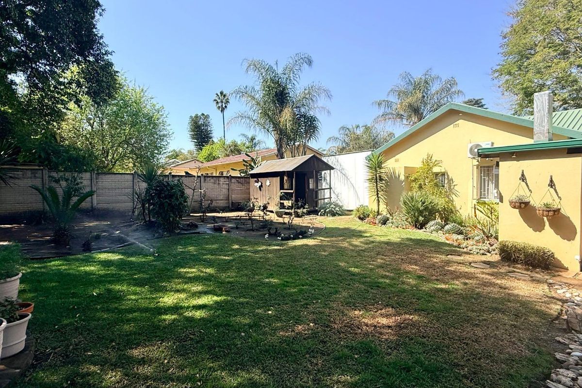 A spacious rear garden featuring a well-maintained lawn, perimeter walling, and a detached garden shed, providing a private outdoor area.