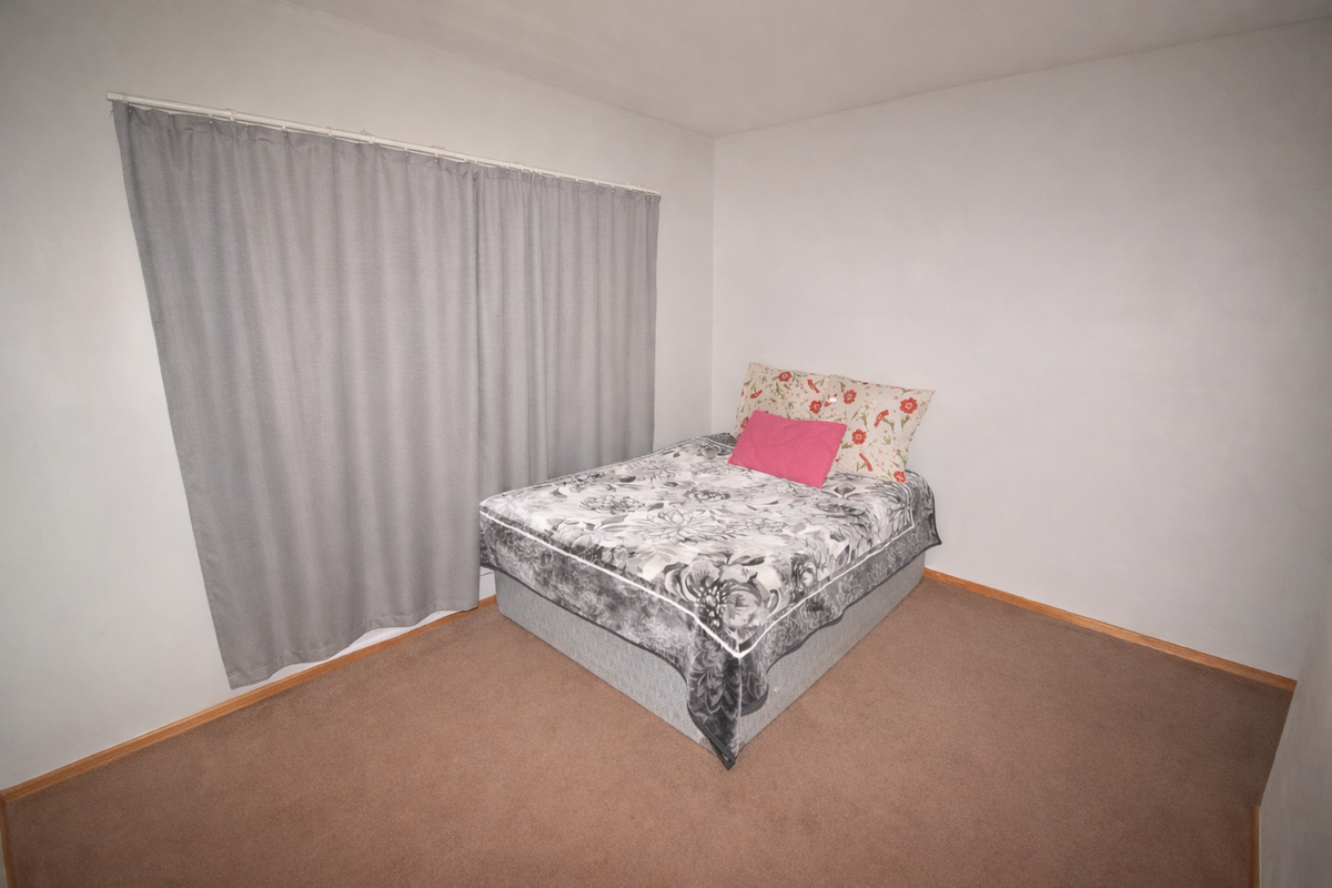 A simple bedroom featuring neutral wall finishes and carpeted flooring, providing a blank canvas for potential interior design updates.