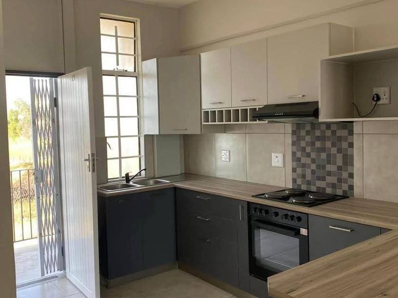 Modern kitchen featuring dark grey and white cabinetry, wood-look laminate countertops, built-in oven, hob, extractor fan, and direct access to a balcony.