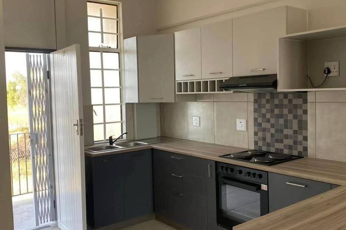 Modern kitchen featuring dark grey and white cabinetry, wood-look laminate countertops, built-in oven, hob, extractor fan, and direct access to a balcony.