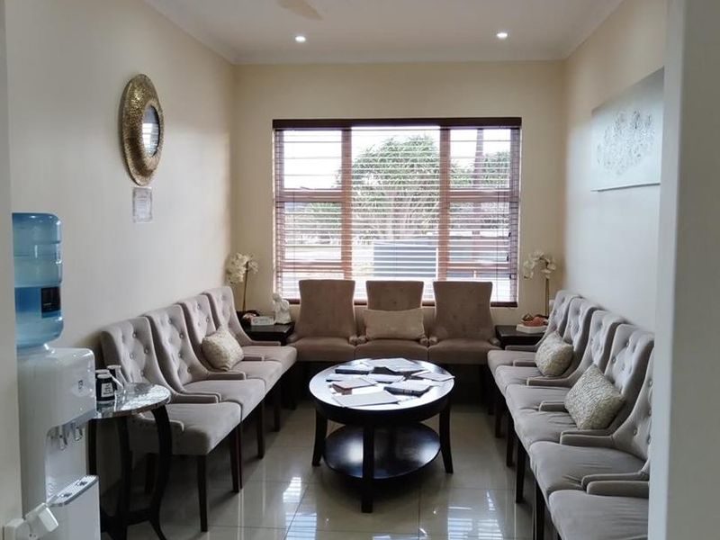 A well-maintained office waiting area featuring polished porcelain floor tiles, recessed downlighting, and large windows with fitted venetian blinds.