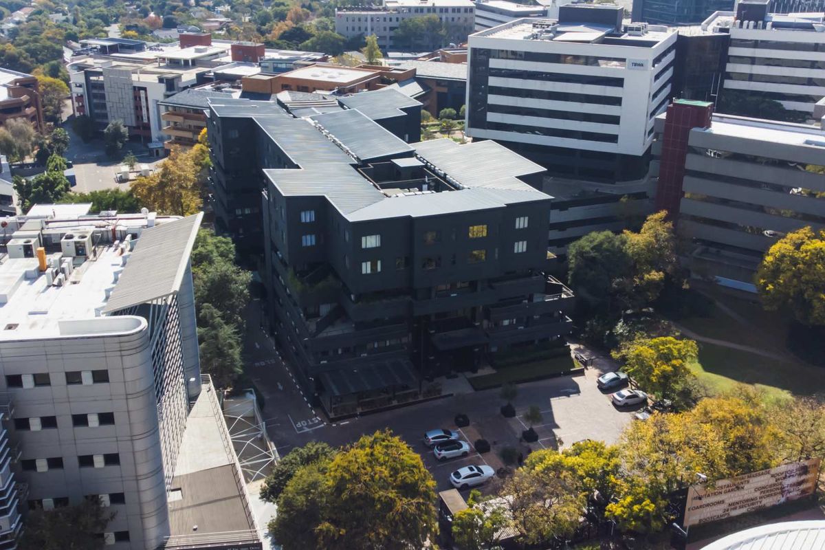 Aerial view of the apartment complex showing the building architecture, surrounding parking area, and urban neighborhood context.