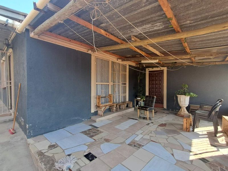 A covered outdoor patio area featuring a corrugated iron roof, timber beams, and tiled flooring, providing a functional space for outdoor living.