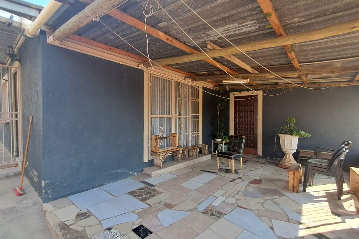A covered outdoor patio area featuring a corrugated iron roof, timber beams, and tiled flooring, providing a functional space for outdoor living.