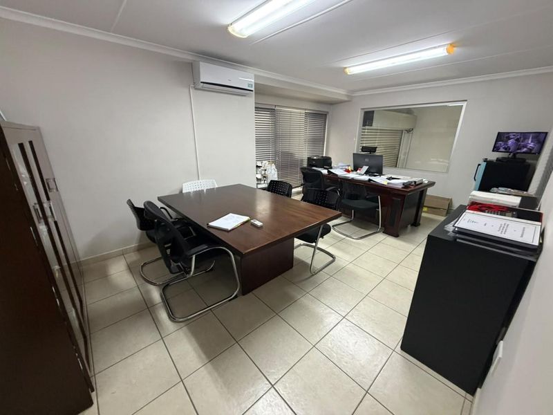 A functional office space featuring tiled flooring, air conditioning, and an internal window, providing a practical environment for professional use.