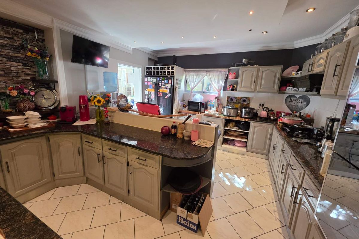 Spacious kitchen featuring granite countertops, ample cabinetry, and tiled flooring, offering a functional layout for meal preparation and storage.