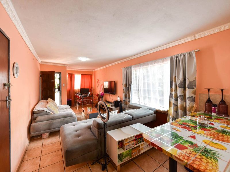 Open-plan living area featuring tiled flooring and ceiling cornicing, offering a functional space with potential for modern updates.