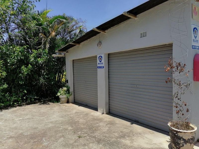 A double garage with roller doors and a concrete driveway, showing signs of exterior wear and weathering.