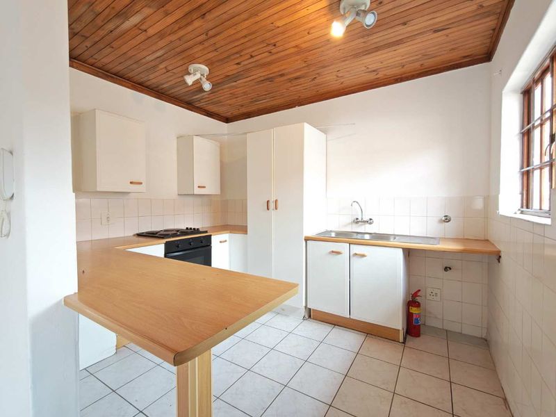 A functional kitchen featuring built-in cabinetry, laminate countertops, a built-in oven and hob, double sink, and a distinctive timber ceiling.