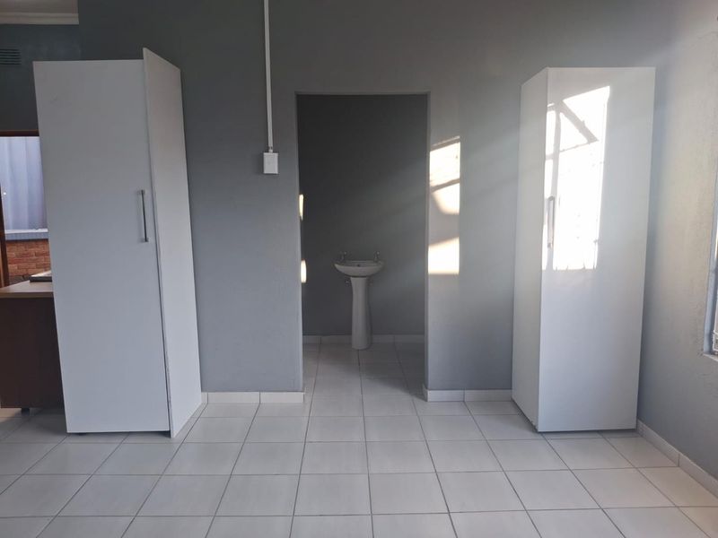 A bedroom featuring tiled flooring, built-in cupboards, and an adjoining alcove with a pedestal basin.