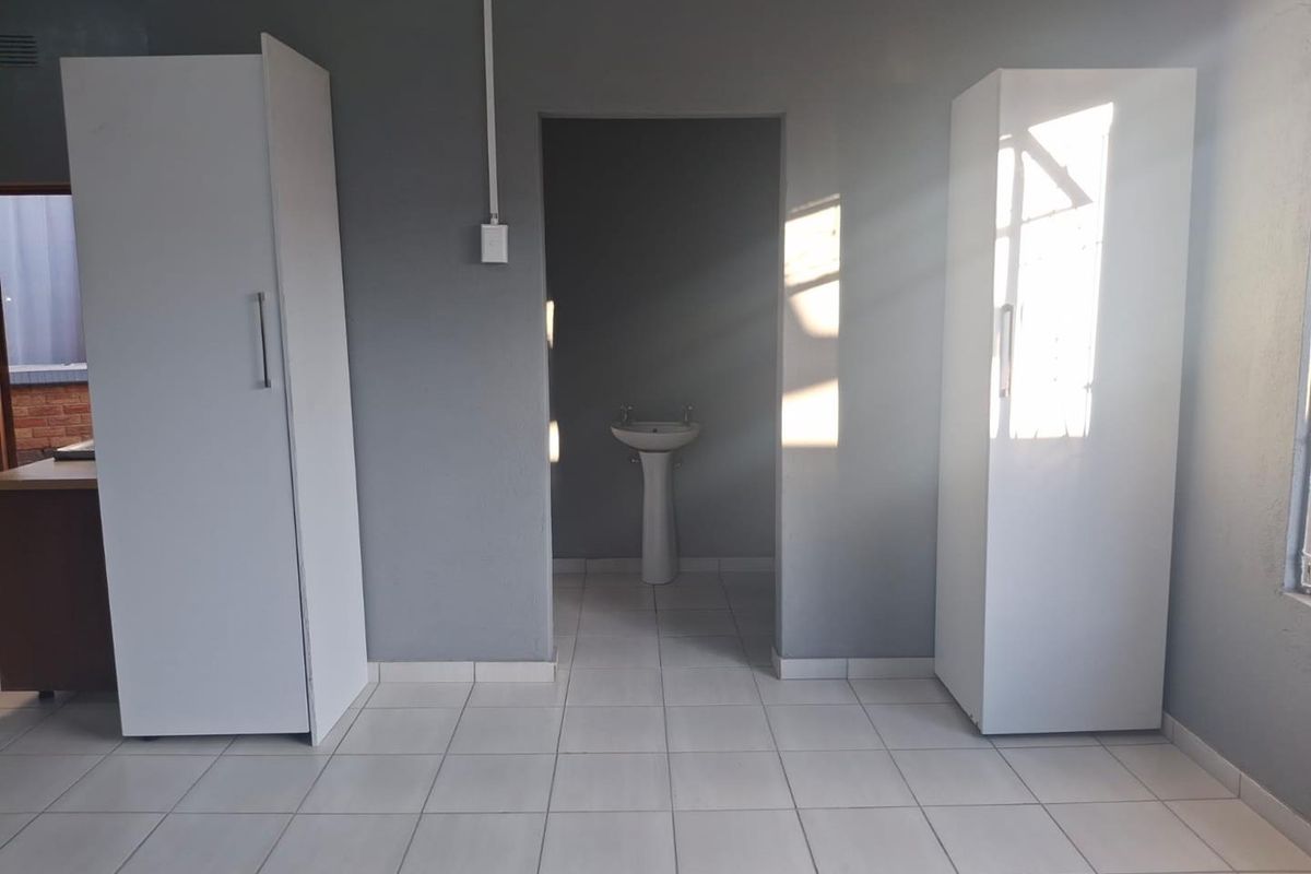 A bedroom featuring tiled flooring, built-in cupboards, and an adjoining alcove with a pedestal basin.