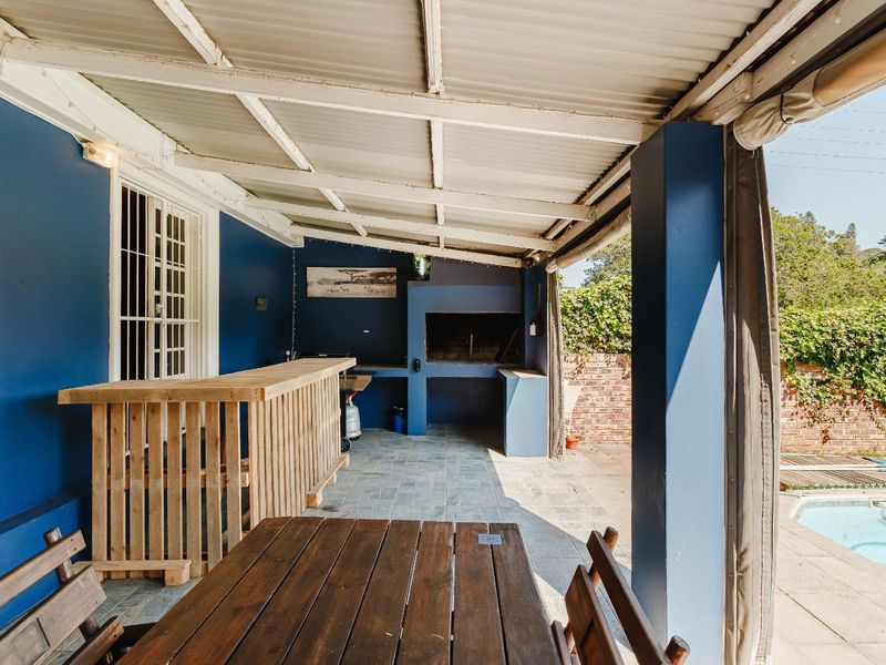 Covered outdoor patio area featuring a built-in braai, tiled flooring, and direct access to the pool area.