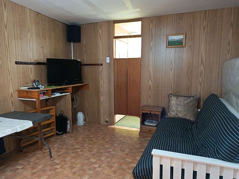 A living area featuring wood-paneled walls and vinyl flooring, requiring cosmetic updates to improve the overall aesthetic and condition of the space.