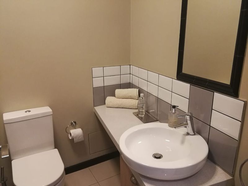 A clean and functional bathroom featuring a modern vanity basin with mixer tap, tiled splashback, and a wall-mounted mirror.