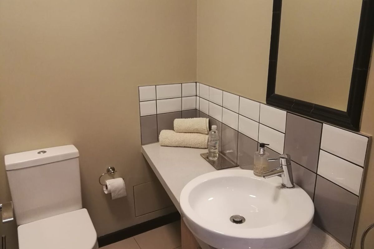 A clean and functional bathroom featuring a modern vanity basin with mixer tap, tiled splashback, and a wall-mounted mirror.