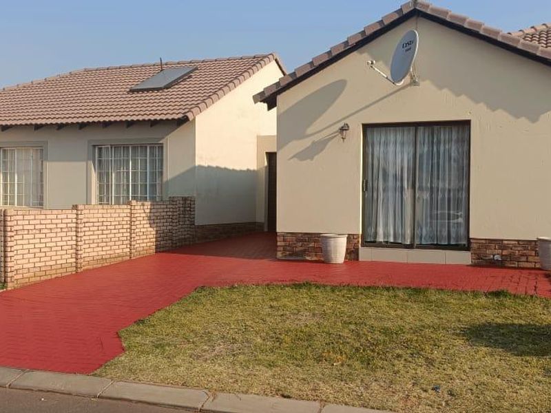Front view of a residential house featuring a tiled roof, brick accents, and a paved driveway area.