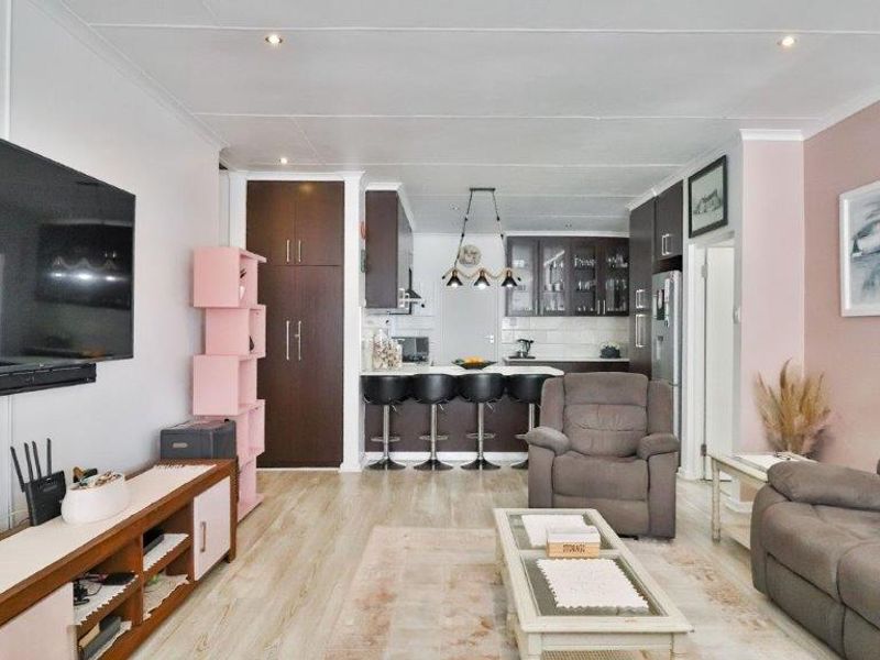Open-plan living area featuring a modern kitchen with dark cabinetry, a central island, and light laminate flooring throughout the combined space.