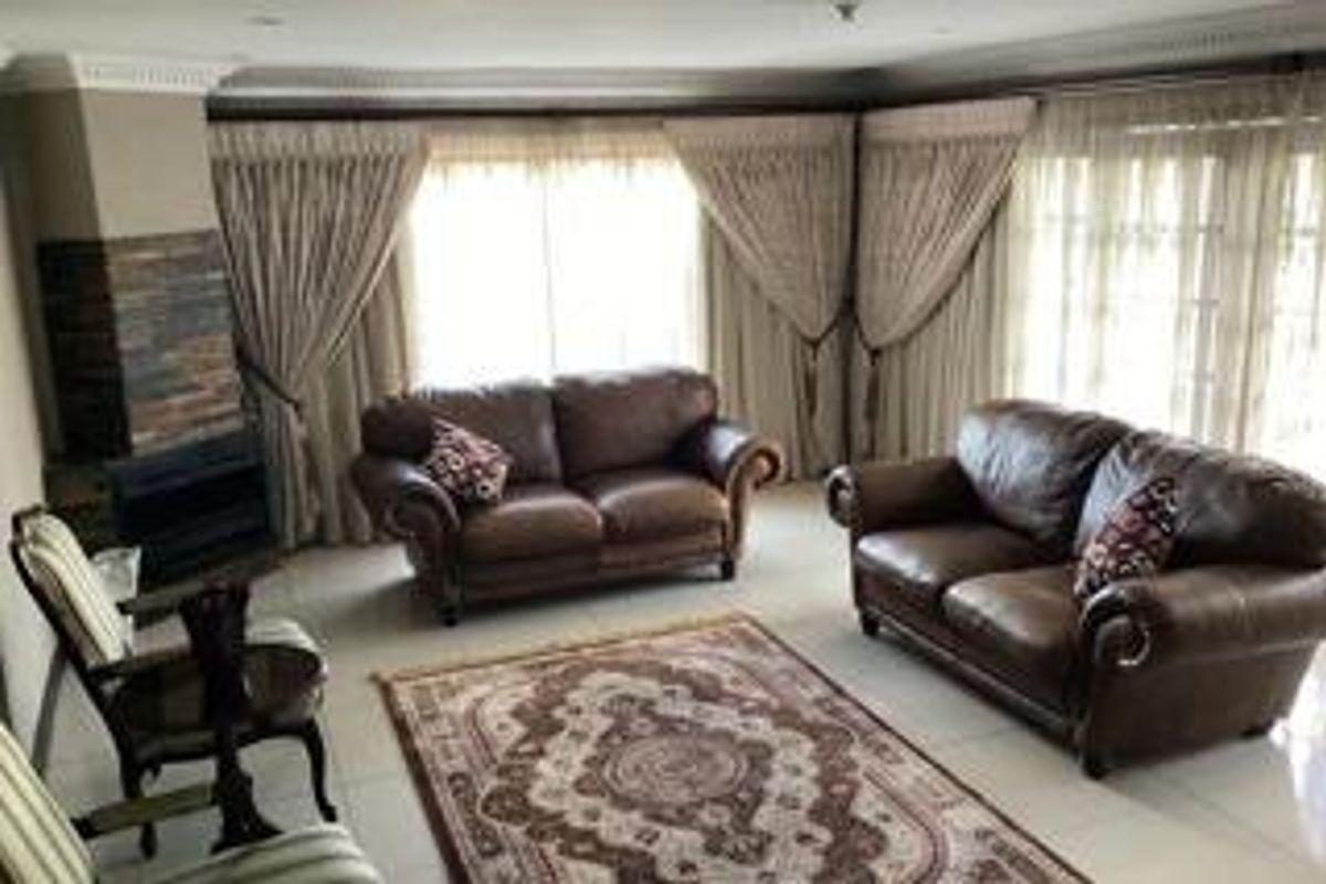 A comfortable living room featuring a built-in fireplace with stone cladding and large windows with floor-to-ceiling curtains.