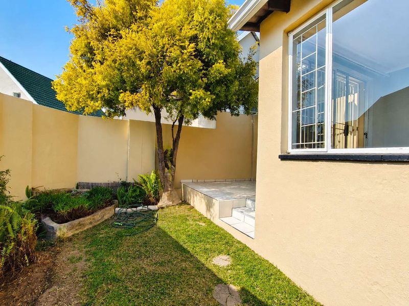 A private rear garden area featuring a tiled patio, a raised garden bed, and perimeter walling, providing a compact outdoor space.