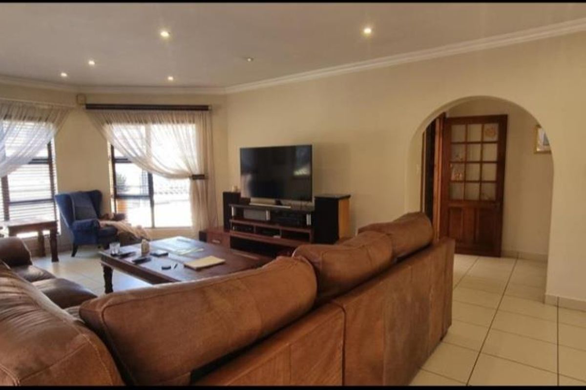 Spacious living room featuring tiled flooring, recessed downlighting, and an arched doorway leading to an adjacent area.