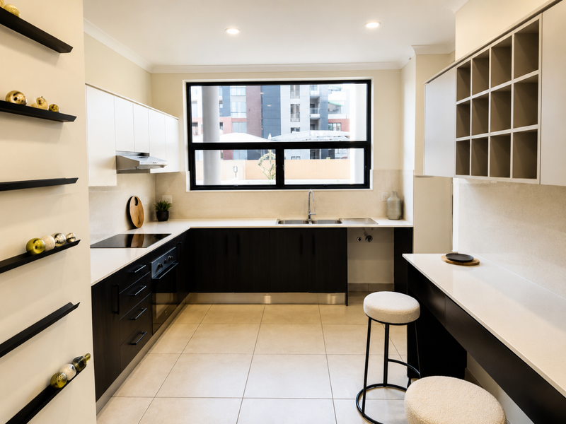 Modern kitchen featuring dark lower cabinetry, white upper cabinets, stone countertops, integrated appliances, and a convenient breakfast bar area.
