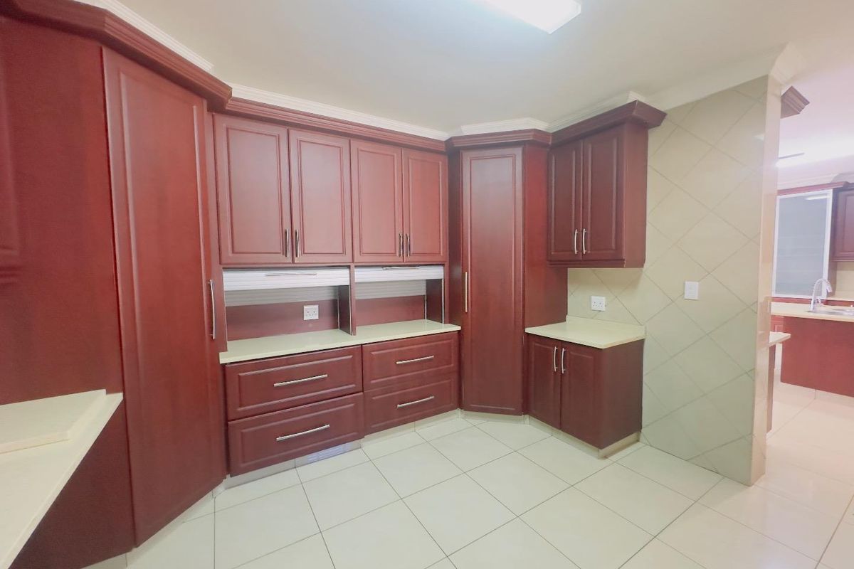 A well-maintained kitchen featuring dark wood cabinetry, light-colored countertops, and tiled flooring, offering ample storage and a clean, functional layout.