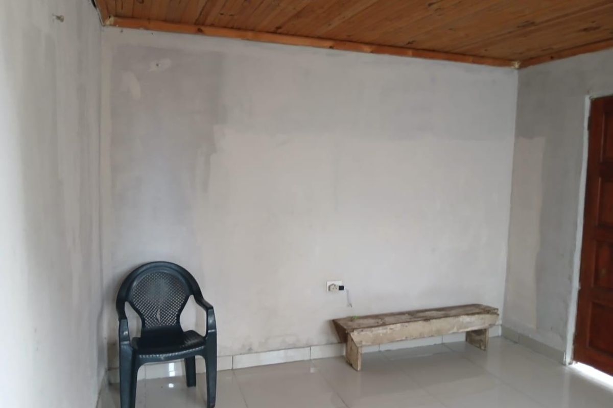 An empty living area featuring tiled flooring and a timber ceiling, currently undergoing wall finishing work.