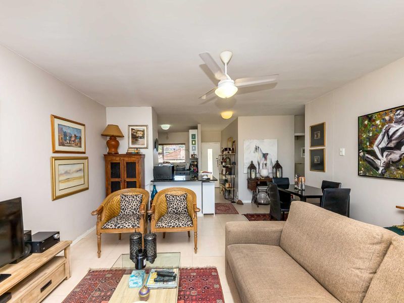 Open-plan living and dining area featuring tiled flooring, a ceiling fan, and a functional kitchen with island cabinetry.