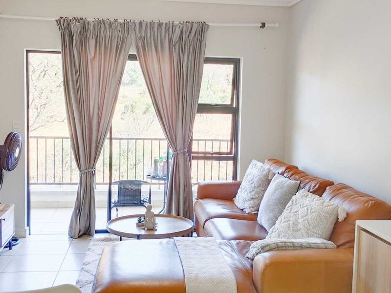 Open-plan living area featuring tiled floors and a sliding glass door leading to a balcony with natural light.