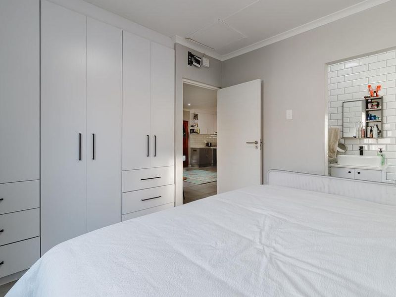 A well-maintained bedroom featuring extensive built-in cabinetry and direct access to an en-suite bathroom with modern subway tile finishes.