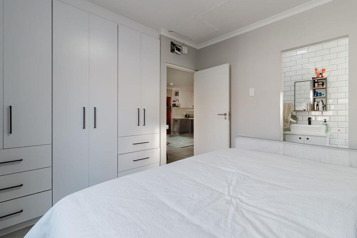 A well-maintained bedroom featuring extensive built-in cabinetry and direct access to an en-suite bathroom with modern subway tile finishes.