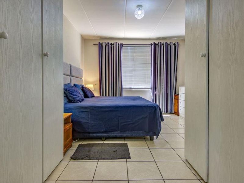 A bedroom featuring tiled flooring and built-in cupboards, viewed from the entrance between two wardrobe units.
