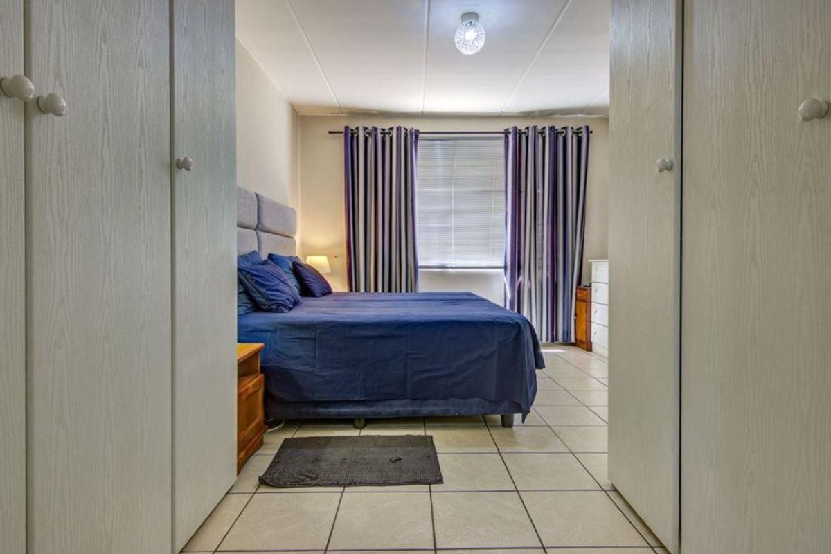 A bedroom featuring tiled flooring and built-in cupboards, viewed from the entrance between two wardrobe units.