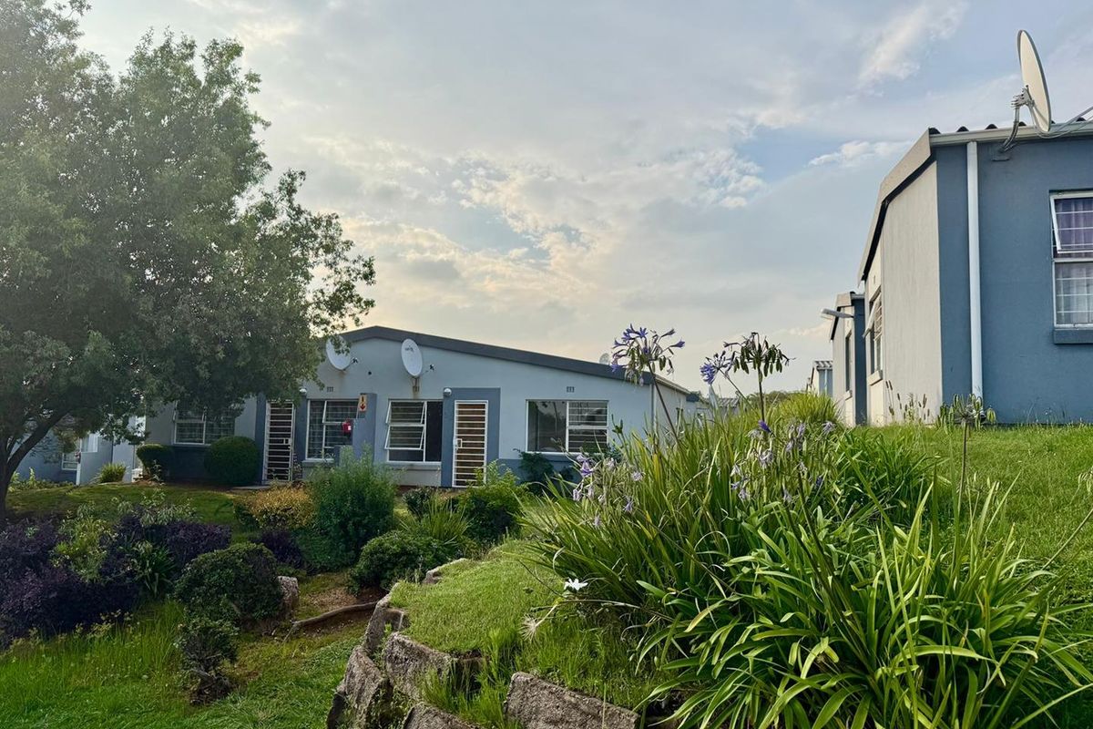Exterior view of apartment units featuring landscaped garden areas, stone retaining walls, and satellite dishes mounted on the building facades.