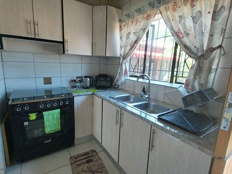 Compact kitchen featuring light-toned cabinetry, a double sink, and a built-in gas stove with an extractor fan.