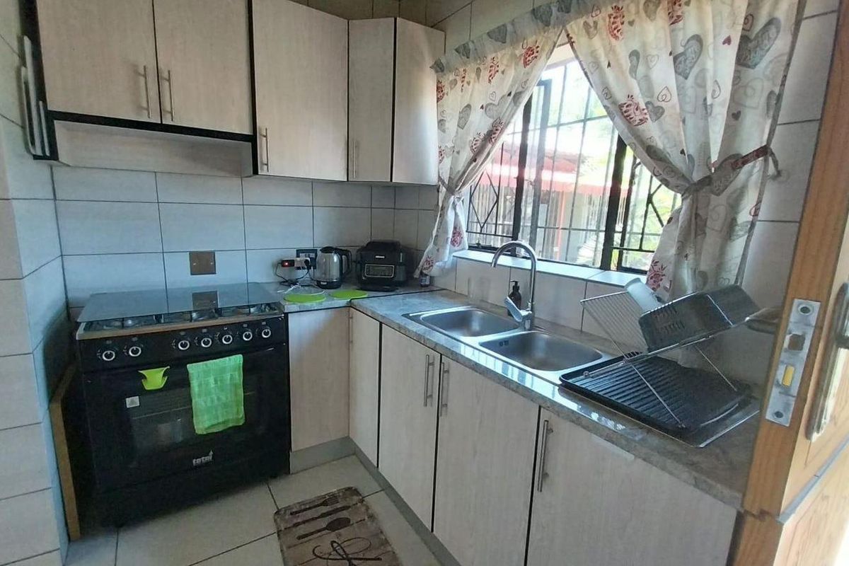 Compact kitchen featuring light-toned cabinetry, a double sink, and a built-in gas stove with an extractor fan.