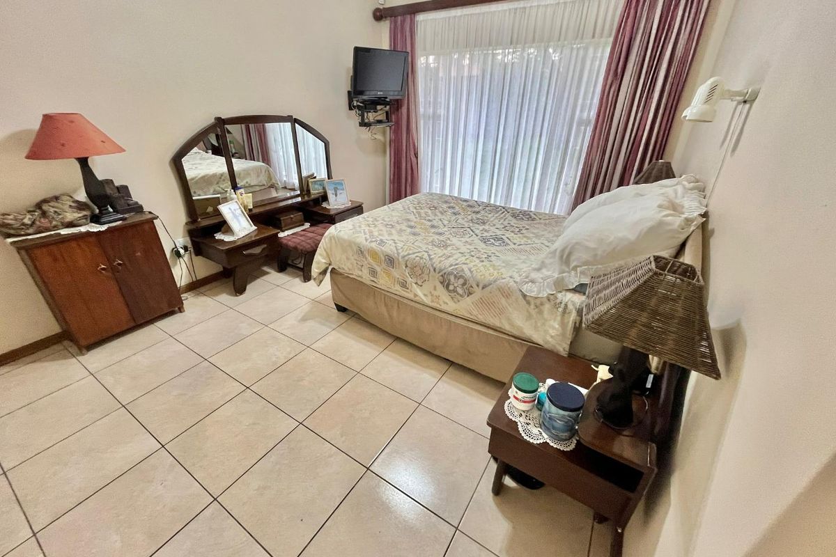 A bedroom featuring tiled flooring and large windows with curtains, providing a functional and comfortable living space.