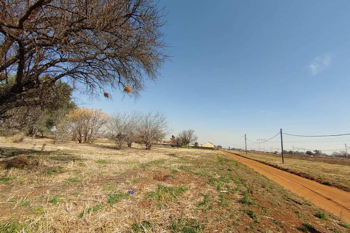 A view of a vacant commercial land plot featuring a dirt road access and existing utility infrastructure.