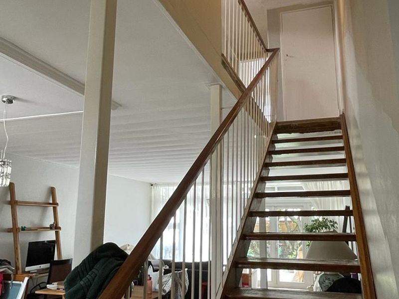 A central staircase featuring wooden treads and a metal balustrade, connecting the living area to the upper level of the townhouse.