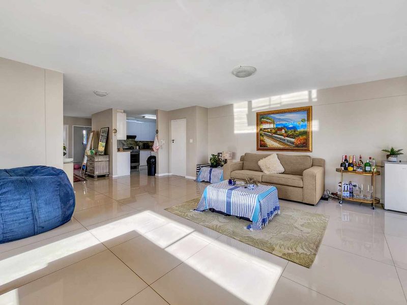 Spacious open-plan living area featuring polished porcelain floor tiles and a seamless transition into a functional kitchen space with modern cabinetry.
