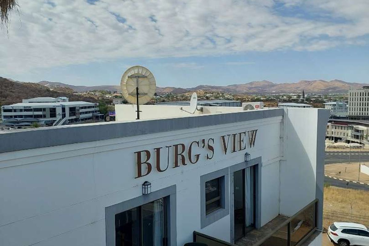 Elevated exterior view of the Burg's View guest house building, featuring a balcony with glass railings and a clear view of the surrounding cityscape.