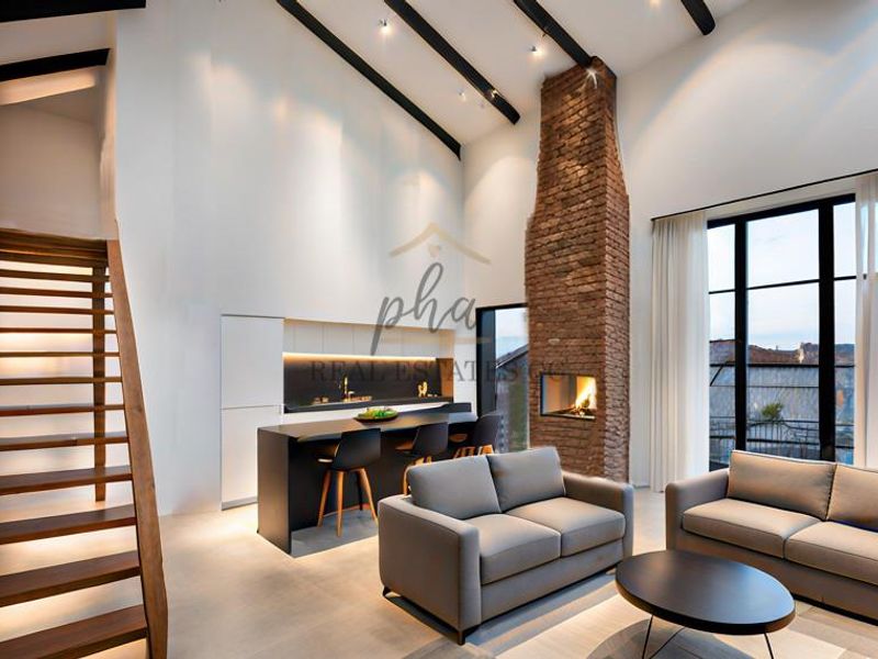 Modern open-plan living area featuring a striking exposed brick fireplace, high vaulted ceilings with exposed beams, and a sleek kitchen with a central island.