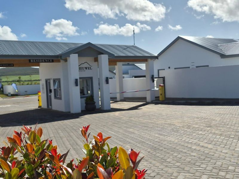The entrance to Heuwel Estate featuring a modern security gatehouse, boom gate access, and paved driveway.