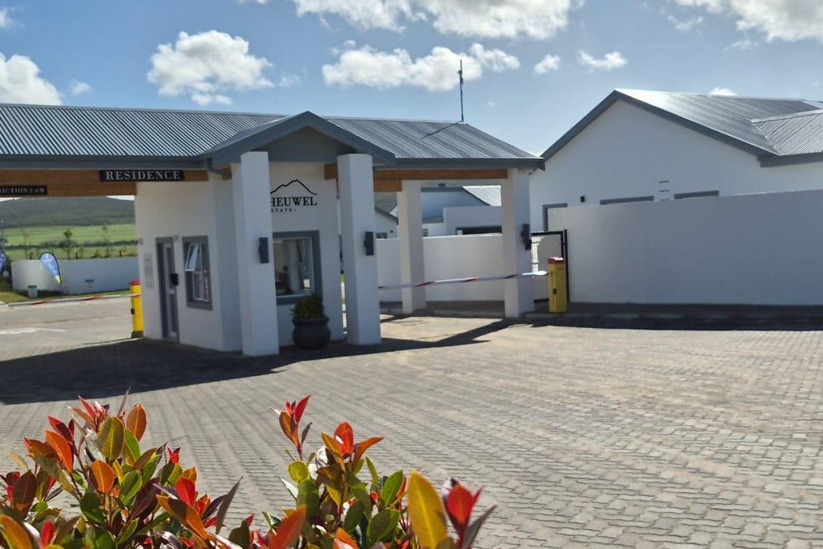 The entrance to Heuwel Estate featuring a modern security gatehouse, boom gate access, and paved driveway.