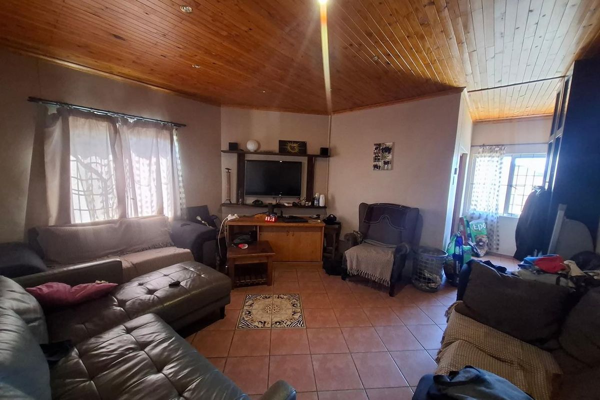 A living room featuring a vaulted timber tongue and groove ceiling, tiled flooring, and a built-in media shelving unit.