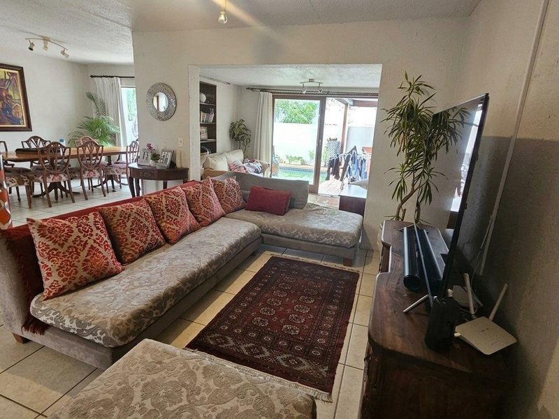 Spacious open-plan living and dining area featuring tiled flooring and large sliding glass doors leading to an outdoor patio space.