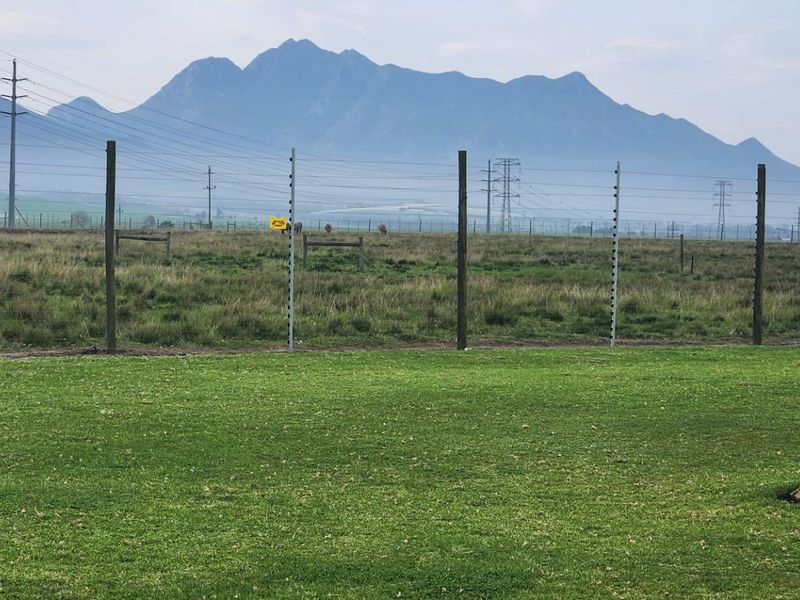 Expansive farm landscape view featuring a manicured lawn, perimeter electric fencing, and scenic mountain vistas in the background.