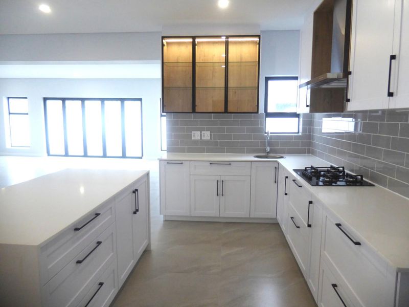 Modern kitchen featuring white cabinetry, quartz countertops, a central island, gas hob, and stylish subway tile backsplash in an open-plan layout.